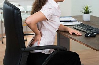 Woman with low back pain sitting in a chair